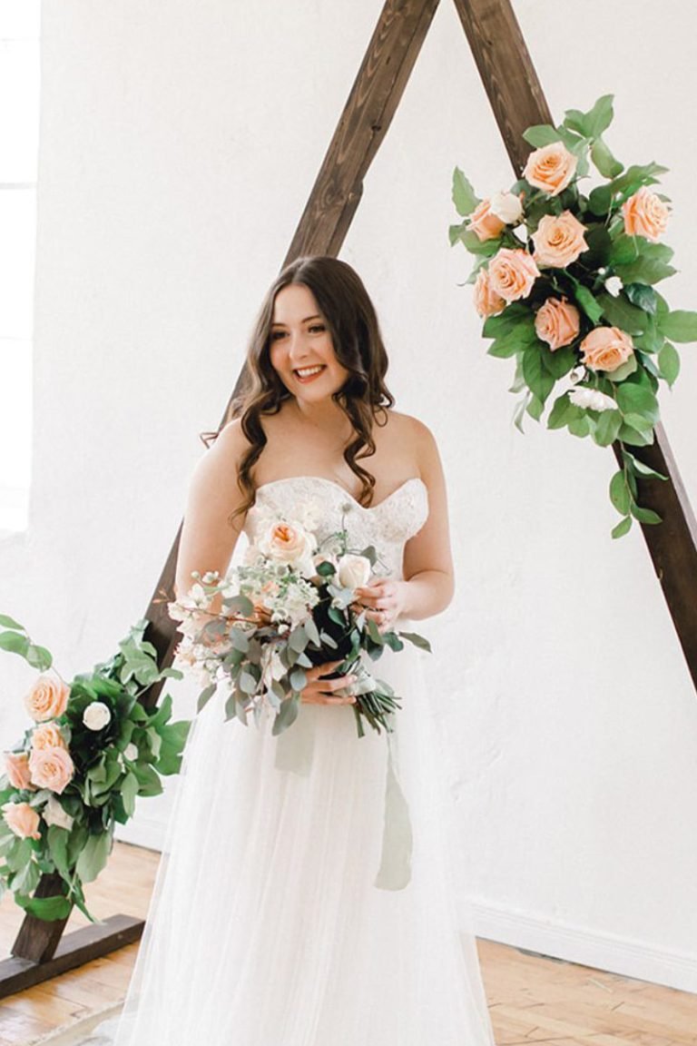 bride with bouquet in front of triangle arbour