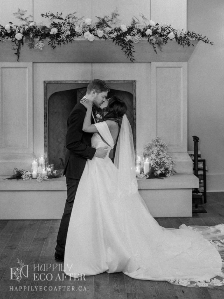 bridegroom kissing in front of a fireplace mantle