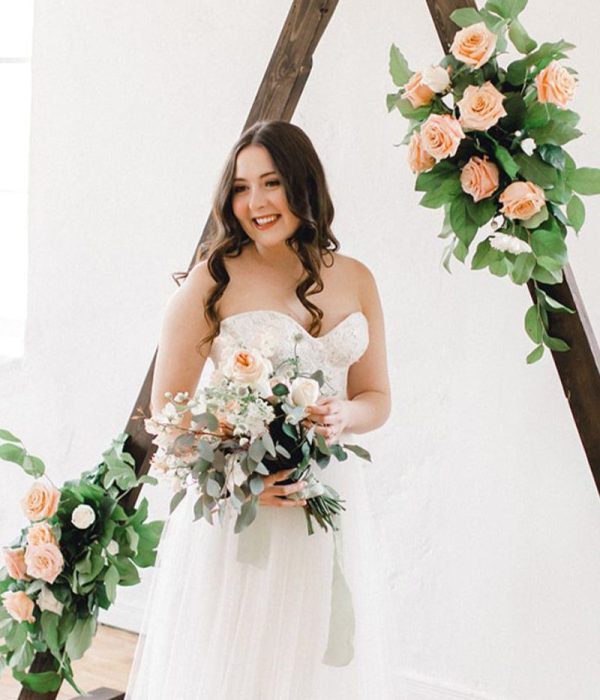 bride with bouquet in front of triangle arbour